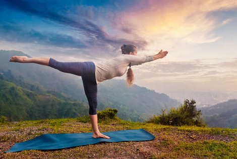 femme pratiquant du yoga, guerrier III, devant un magnifique lever du soleil printanière en haut d'un montagne