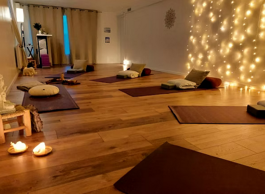 salle de yoga calme chaleureux allumé par bougie avec tapis, coussins, et bolsters de yoga